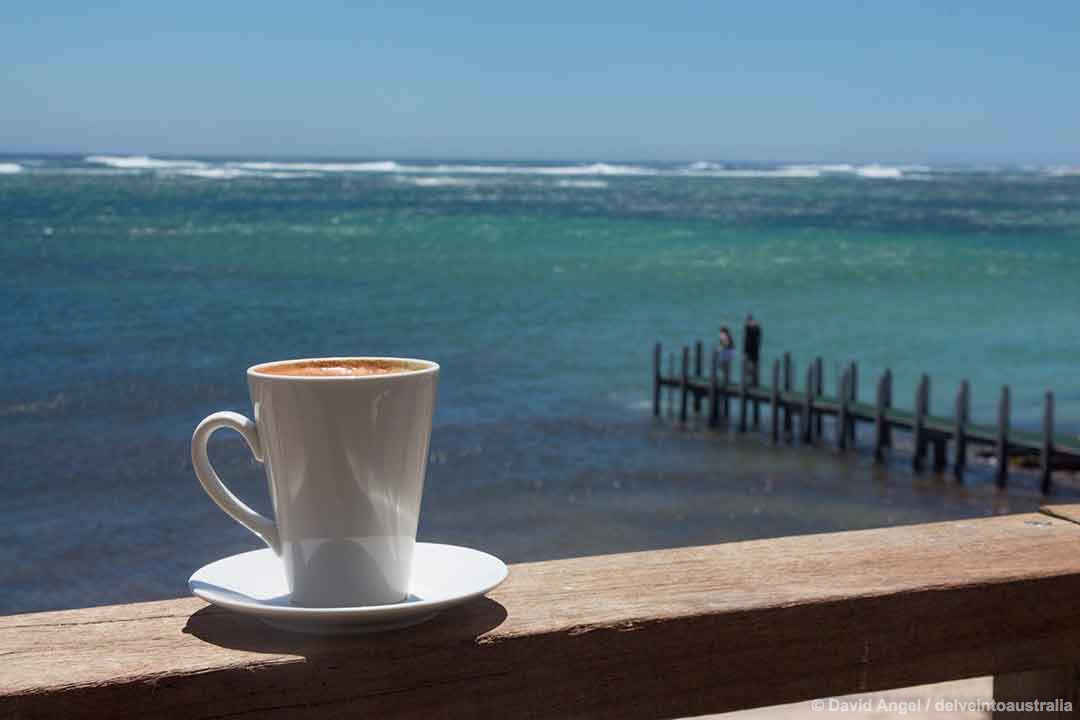 Image of a cup of coffee with Gnarabup Beach and the Indian Ocean in the background